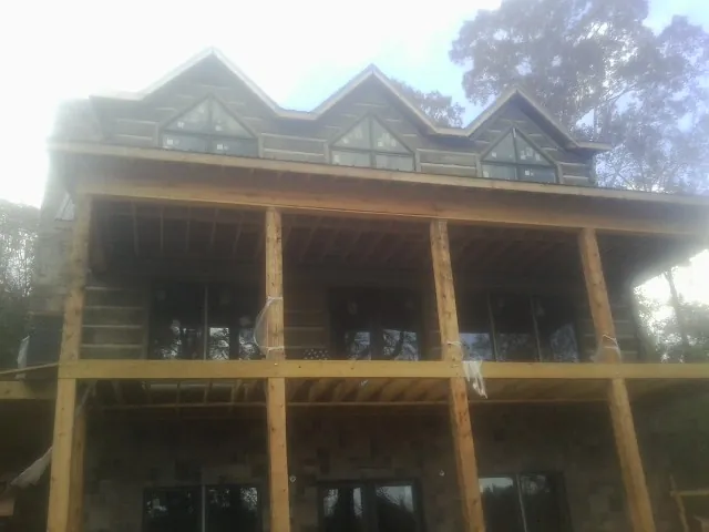 Dormers and porch framing on a large log home under construction — Roof Coating work by our crew in Ranchos De Taos